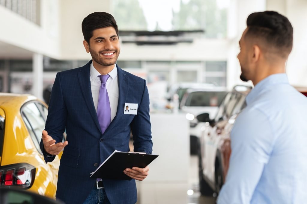 Cheerful car salon manager having conversation with male customer